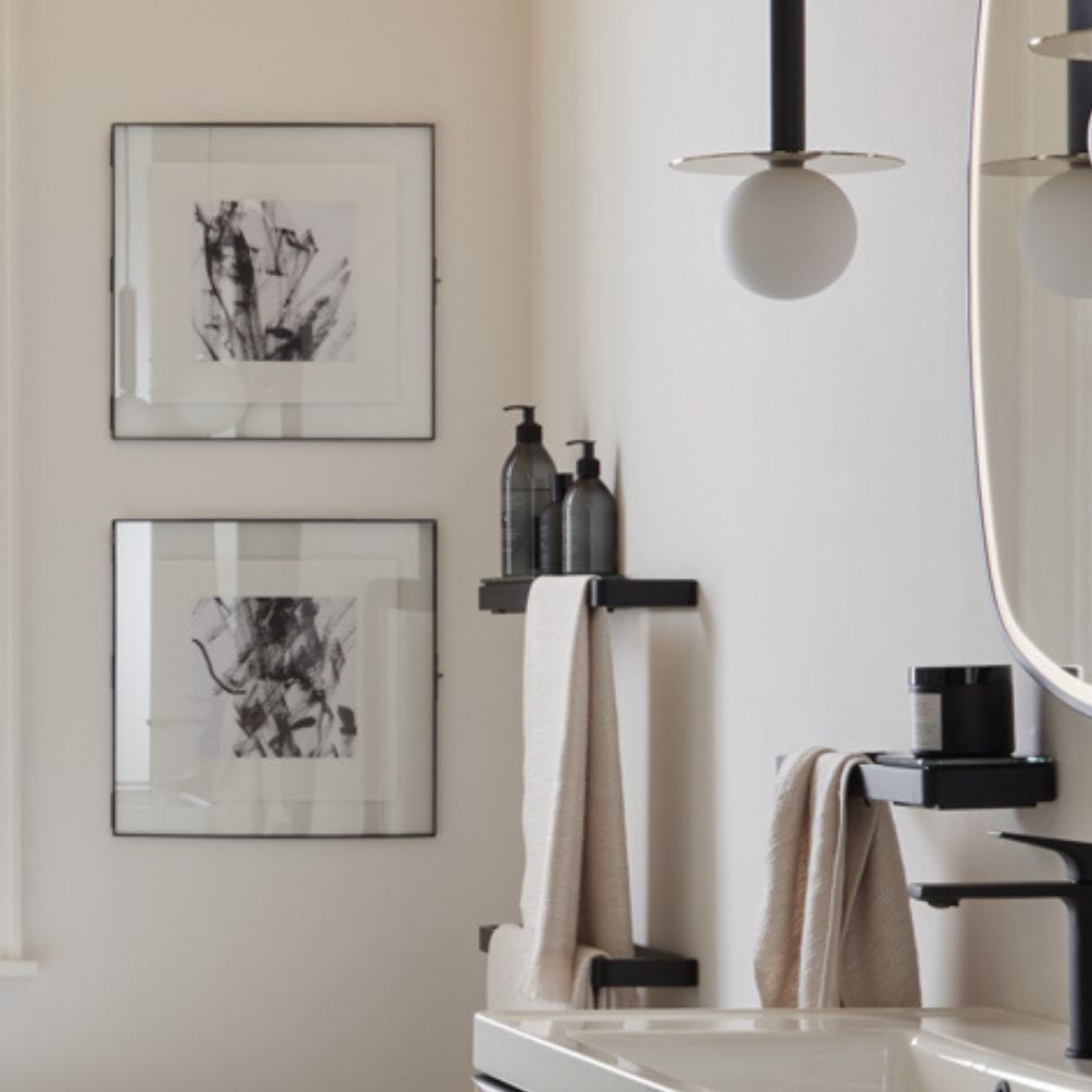 lifestyle image of vado cameo muse 300mm black glass shelf insert and black shelf frame in bathroom for bottles with towel hanging beside MUS-085-30-BLK and MUS-184-60-MB